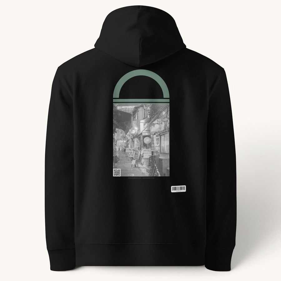 ETHIKKALL sweat à capuche unisexe noir en coton organique avec un imprimé de rue tokyoïte encadré par une arche verte.